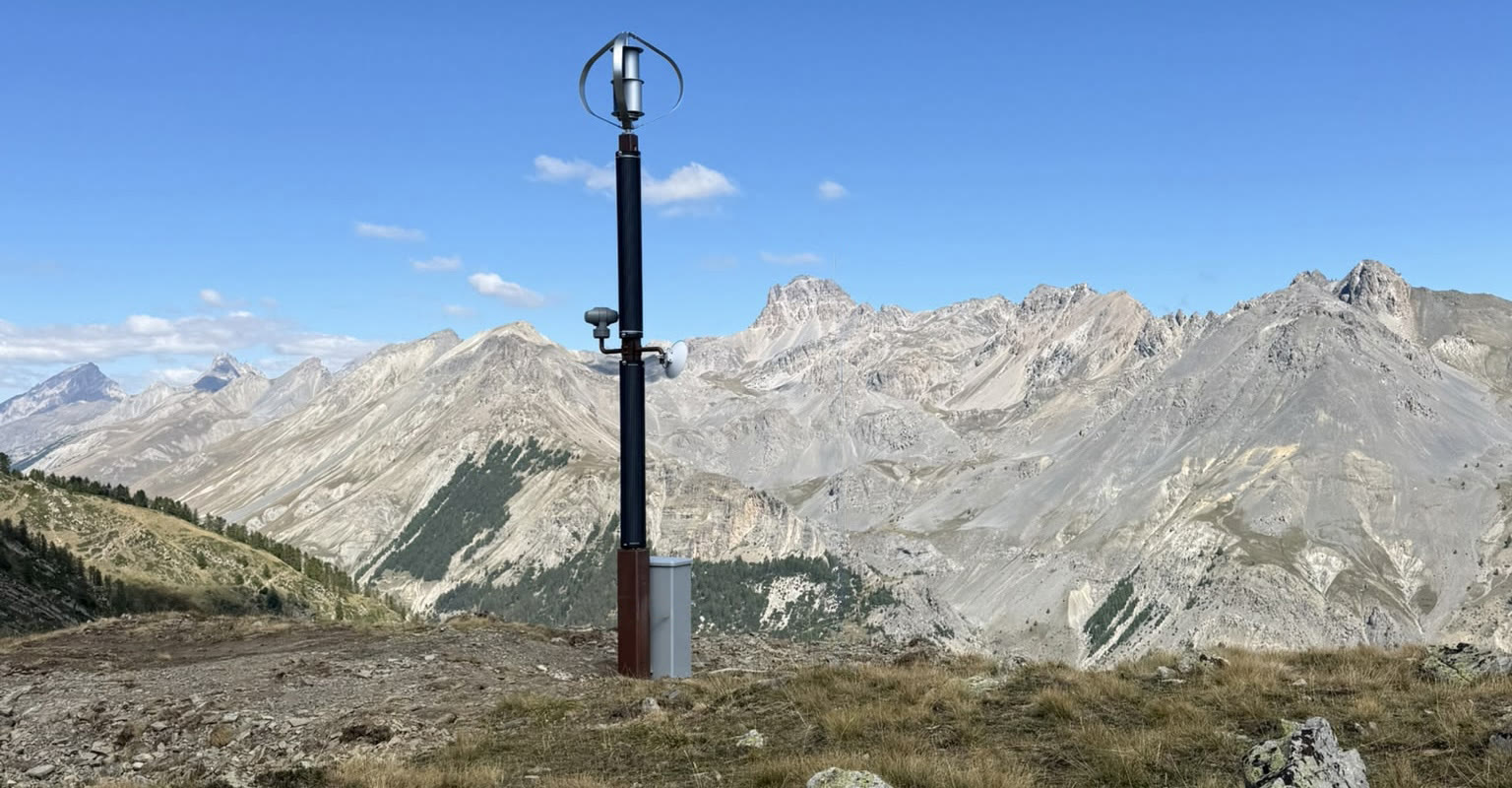 Il palo smart di Argentera con pala eolica e telecamera davanti alle montagne dell'alta Valle Stura, a oltre 2.300 metri