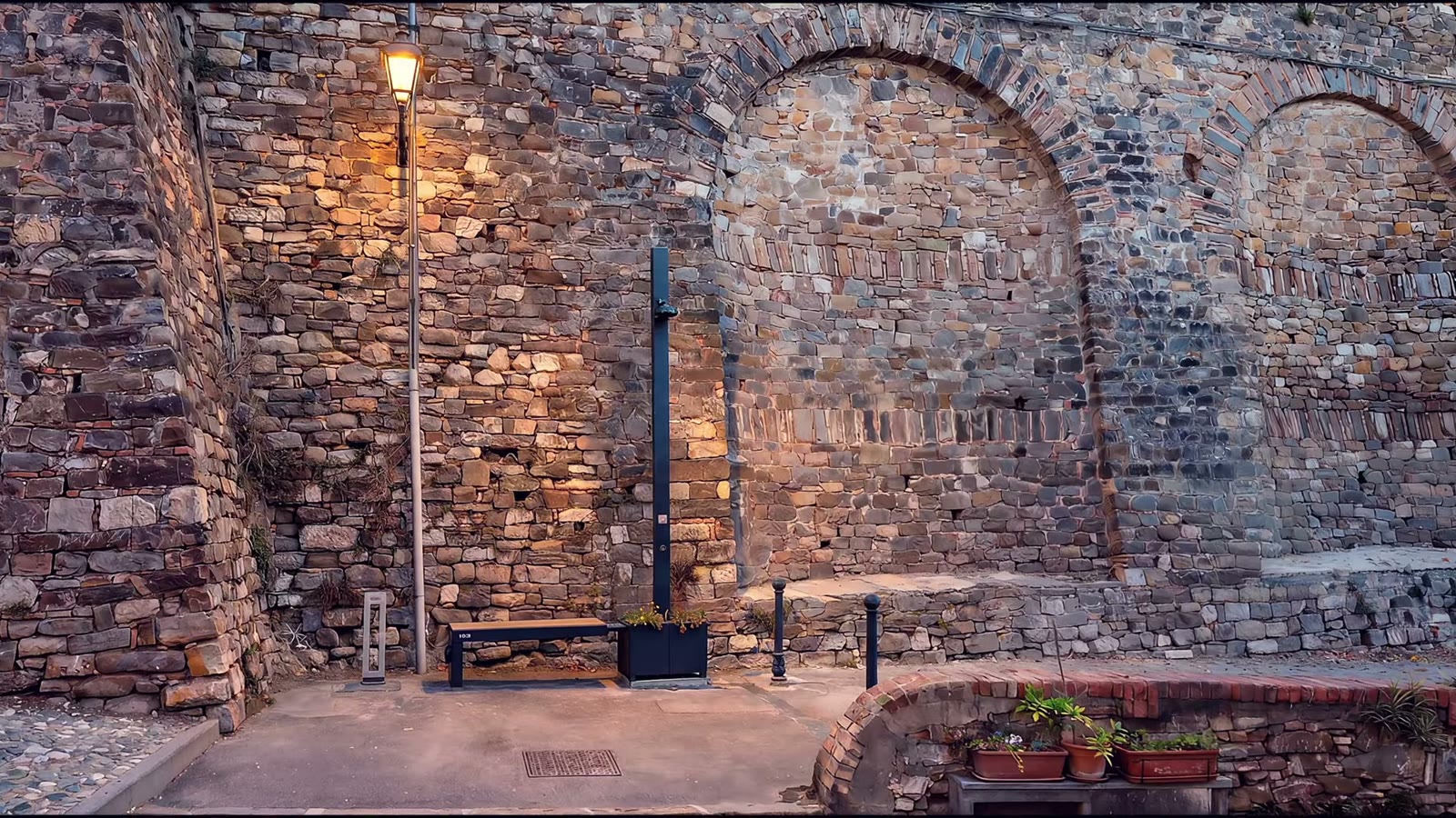 Isola smart e panchina davanti al muro medievale con archi in pietra nella Pigna