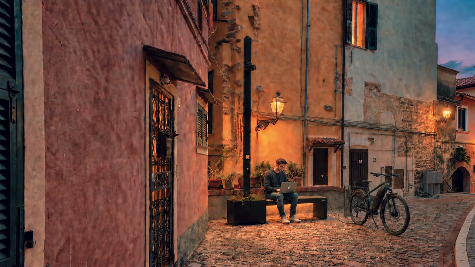 Un ragazzo usa la panchina smart con la sua e-bike in una piazzetta della Pigna